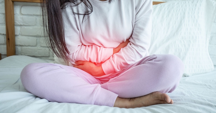 woman have bladder pain sitting on bed in bedroom after wake up; blog: urinary tract infections
