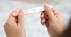 Woman hand holding pregnancy test and result is not pregnant; infertility raleigh nc