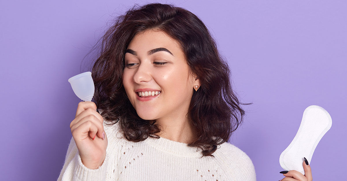 Woman holding menstrual cup and sanitary pad in hands. Feminine hygiene alternative product instead of tampon during her period. Menstruation, critical days, zero waste, eco, ecology concept; blog: What is Menstruation Awareness?