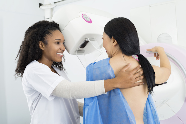 Happy Doctor Assisting Woman Undergoing Mammogram X-ray Test; blog: When Should I Get a Mammogram?