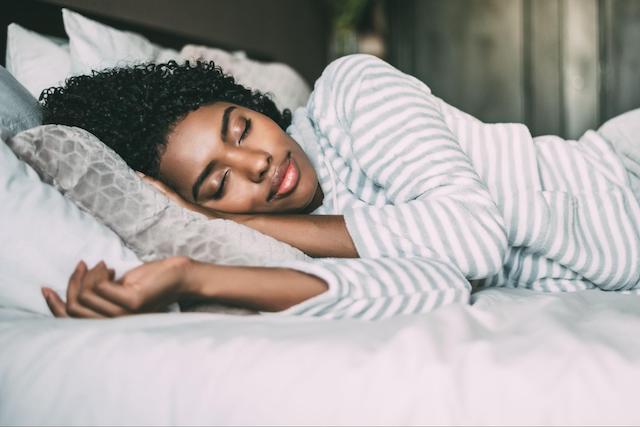 a woman sleeping soundly in bed to represent tips for better sleep
